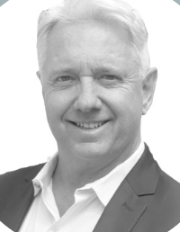 Black and white portrait of Huaye Zhang, Google AI Advisor at Turba Media, smiling and wearing a striped sweater in front of a natural background.