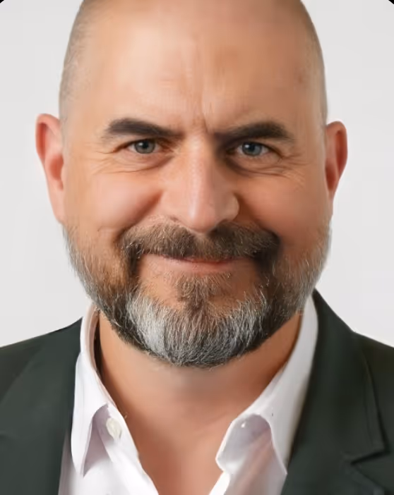 Black and white headshot of Stuart Maclean, IBM AI Advisor at Turba Media, smiling and wearing glasses and a lanyard.