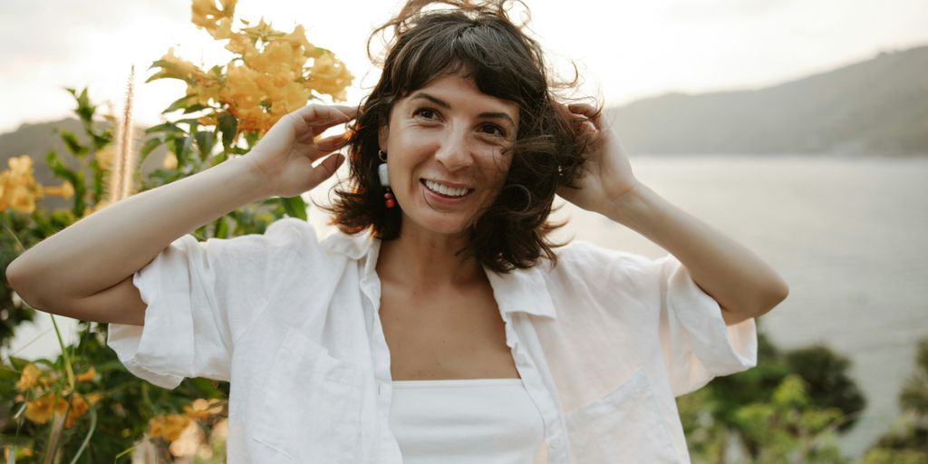 a woman in a white shirt is holding her hair