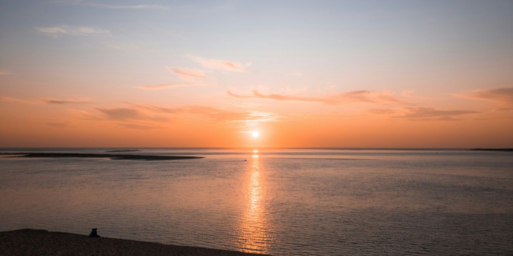 a person sitting on a beach watching the sun set