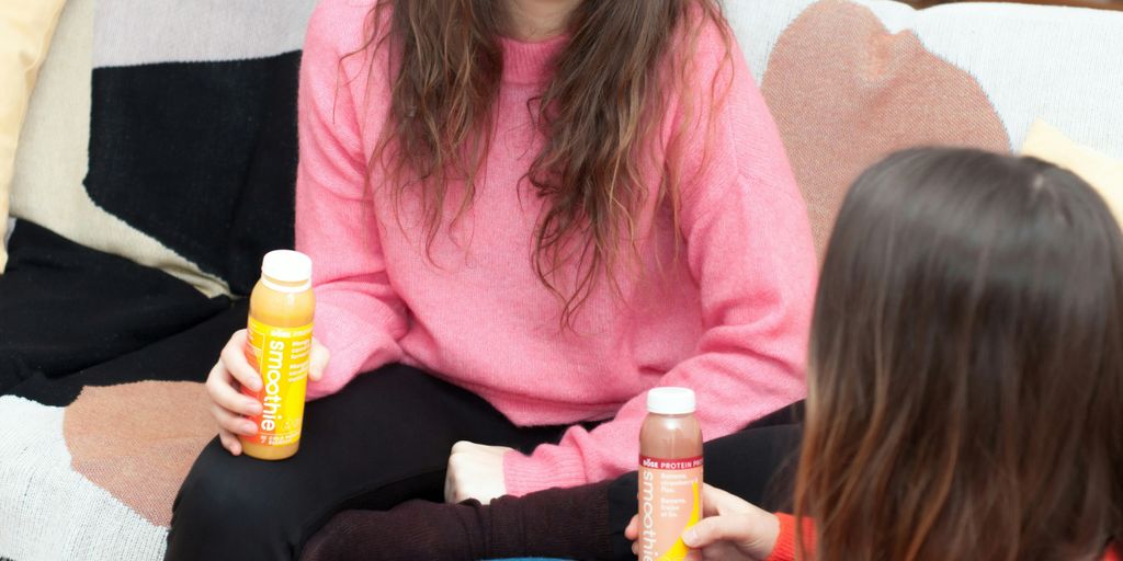 two women holding smoothie bottles