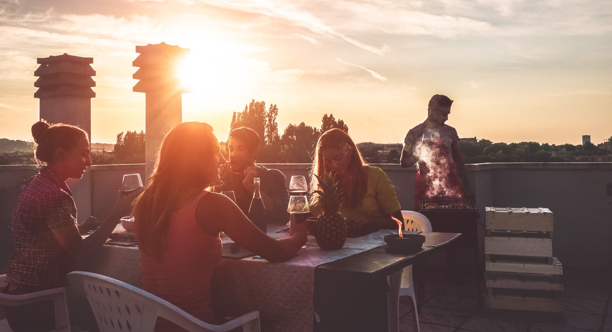 people on a roof deck socialising and drinking and dining during sunset