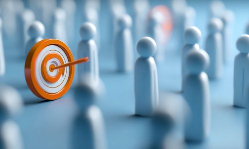 Orange and white target with an arrow in the center standing among blurred white figurines on a blue surface.