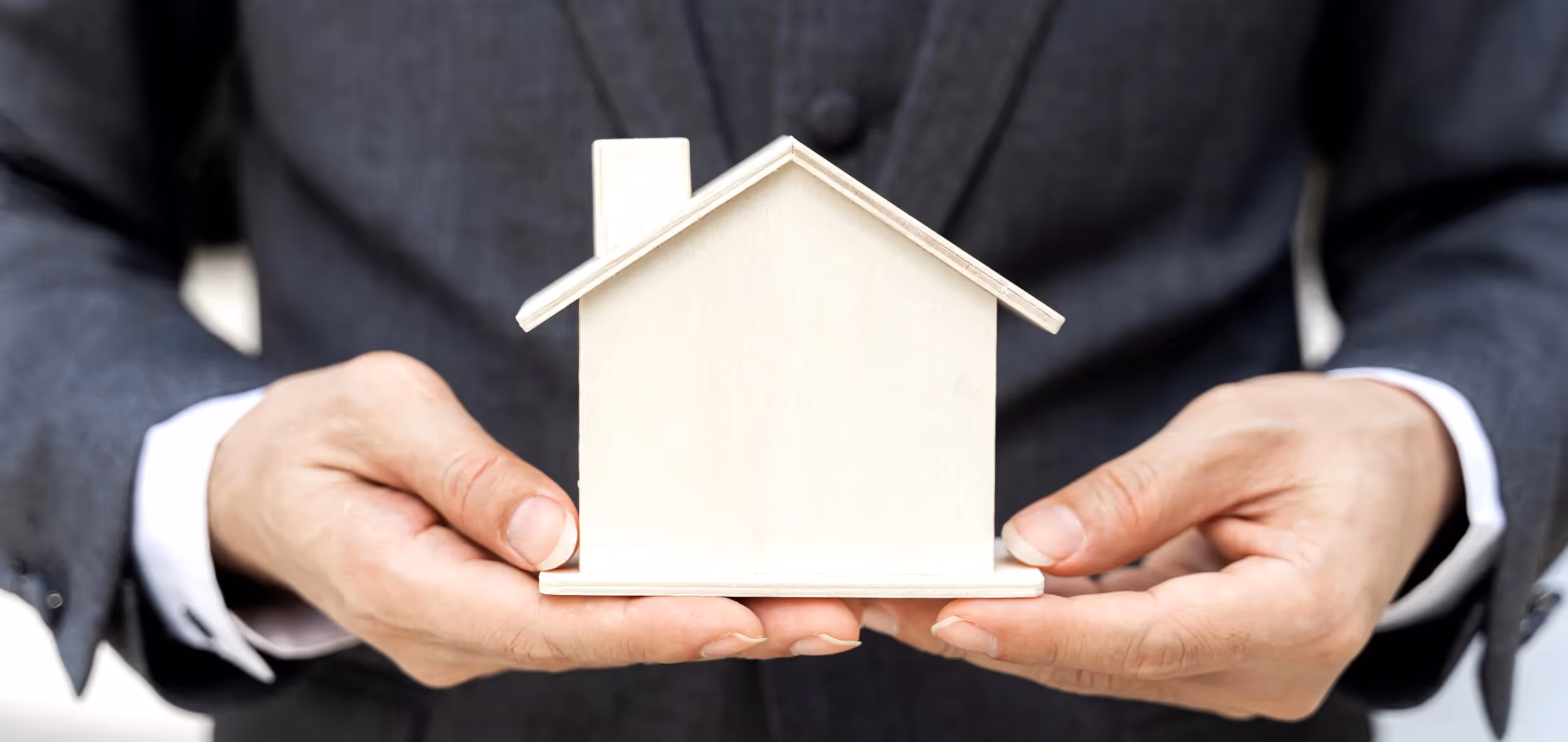 un homme tient une maison en bois dans ses mains.