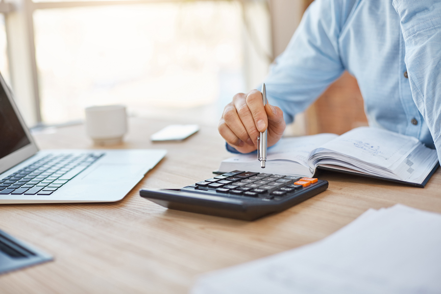 Un homme tient un stylo dans sa main et tape sur une calculatrice
