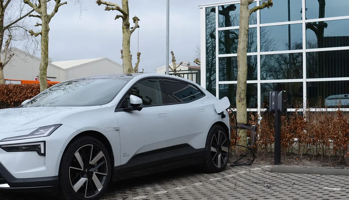 Borne de recharge Qobox P installée en extérieur sur un parking d'entreprise, véhicule électrique en charge
