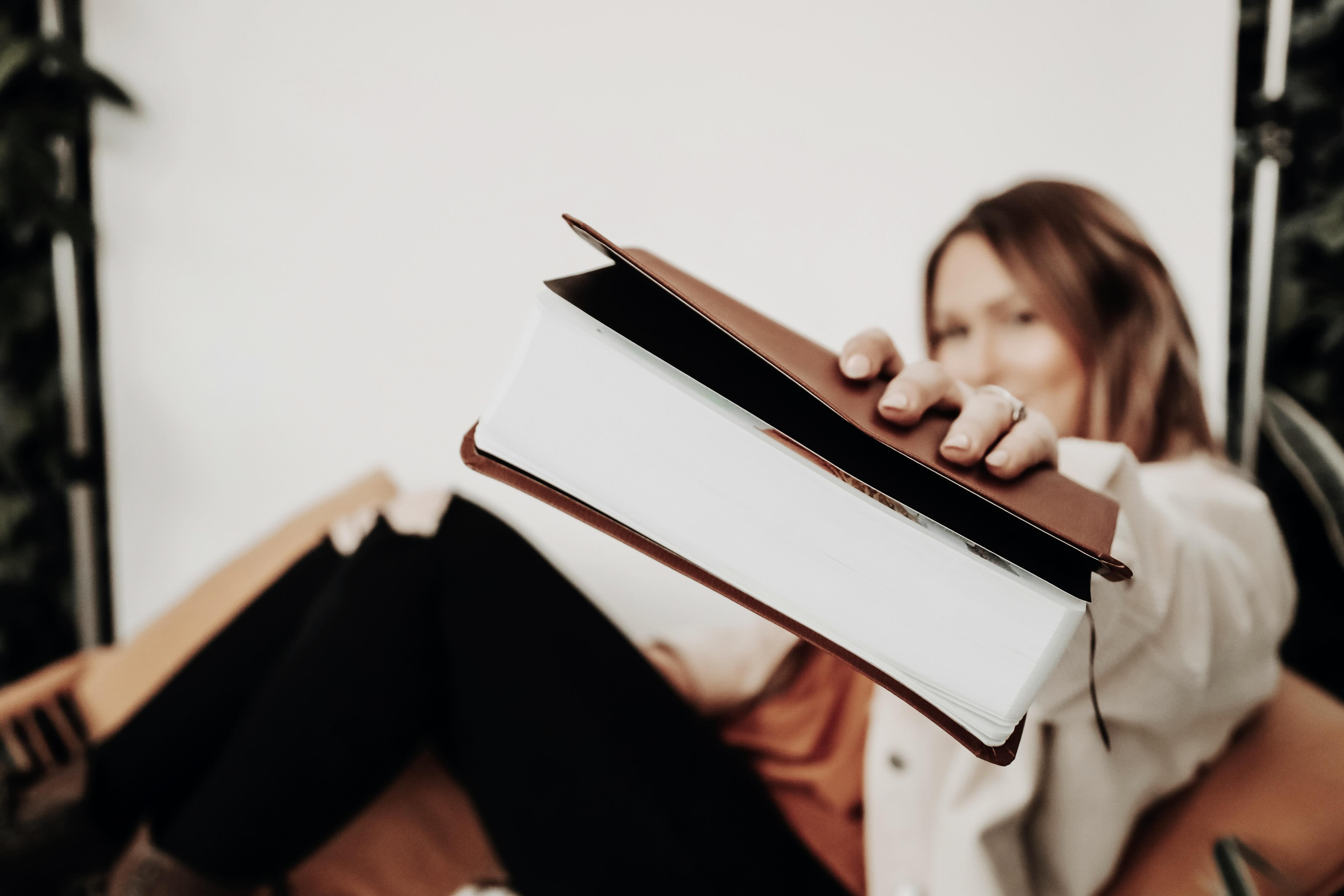 Eine junge Frau hält eine große Bibel in die Kamera, Fokus auf christliche Ressourcen.