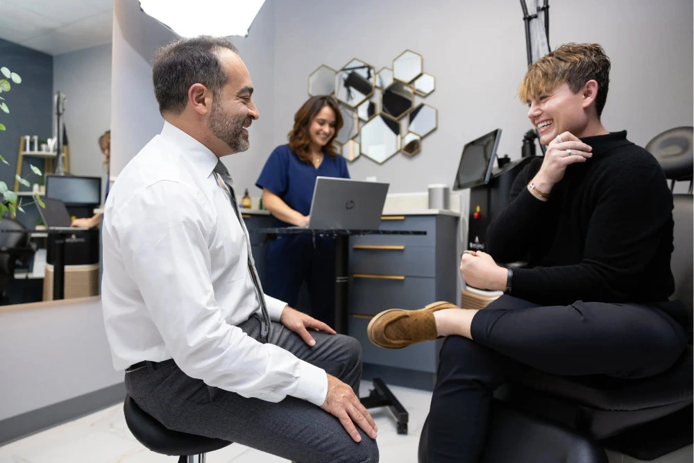 The Pain Free Institute consultation with a doctor using a spine model to explain non-surgical pain care to a patient in a calm, upscale medical office