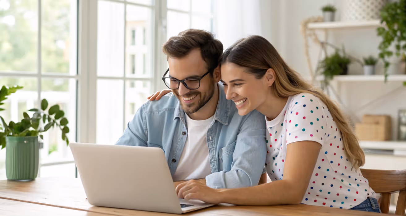 Happy couple reviewing mortgage options on a laptop at home, symbolizing the appraisal process during refinancing decisions.
