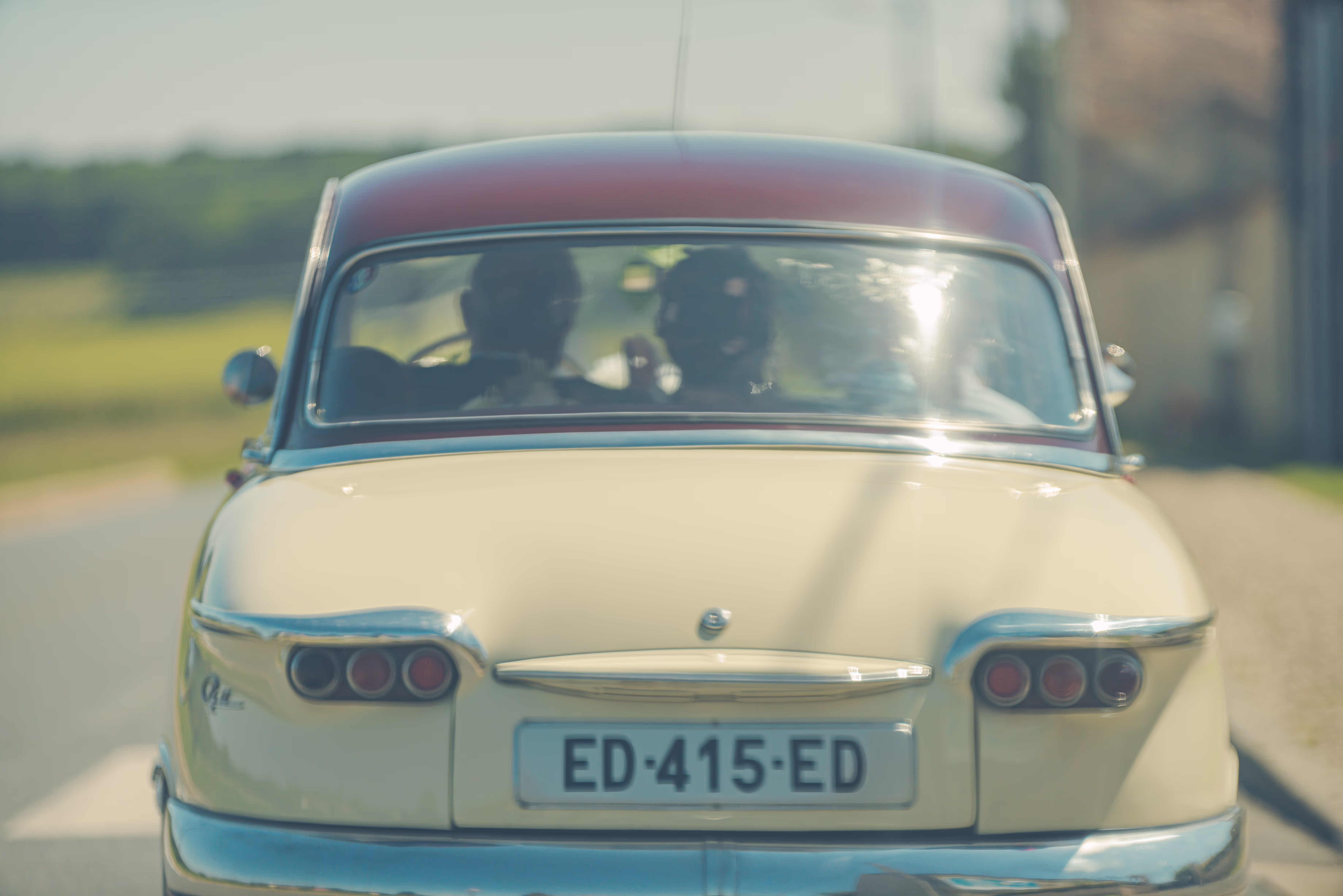 Une belle voiture rétro vue de derrière, avec les mariés à l'intérieur
