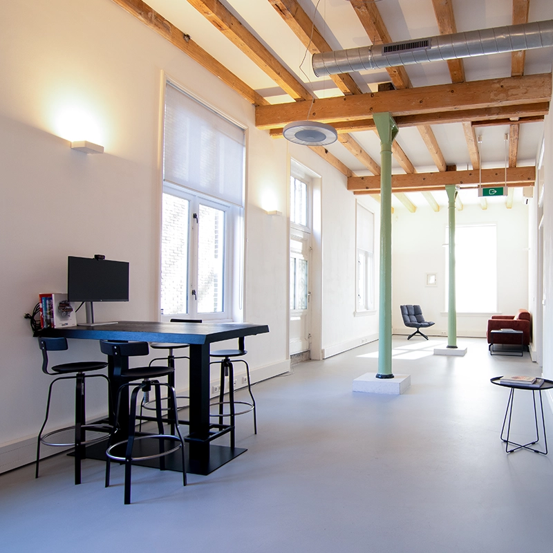 Een hoge tafel met barstoelen en een tv aan de muur