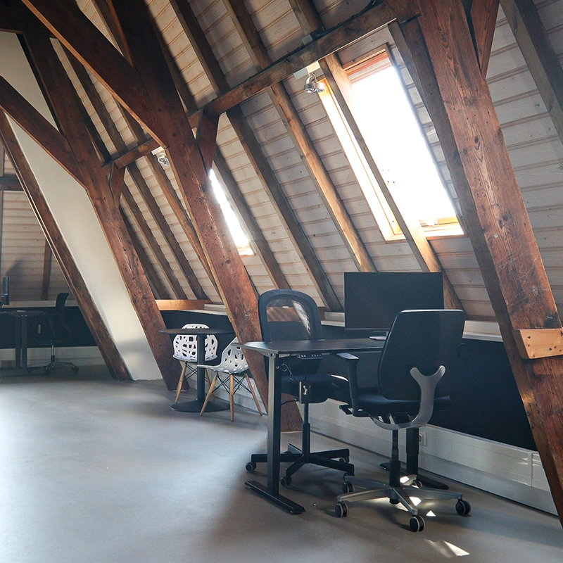 2 bureaus met stoelen en een computer en een tafel met 2 stoelen