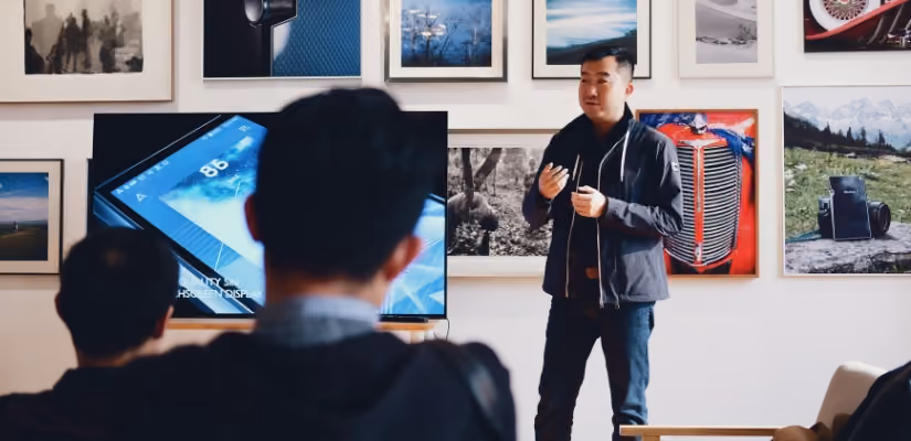 Chatbot conference speaker presenting with screen in art-filled room. Ideal for tech event content.