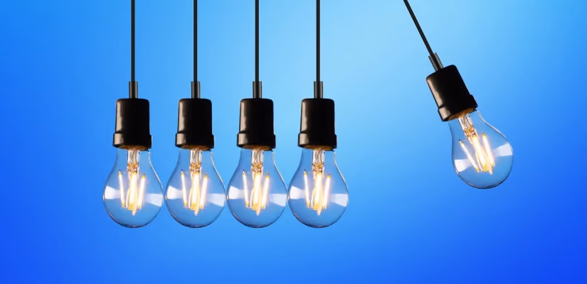 Five hanging light bulbs against blue background, illustrating innovation and creativity concepts.