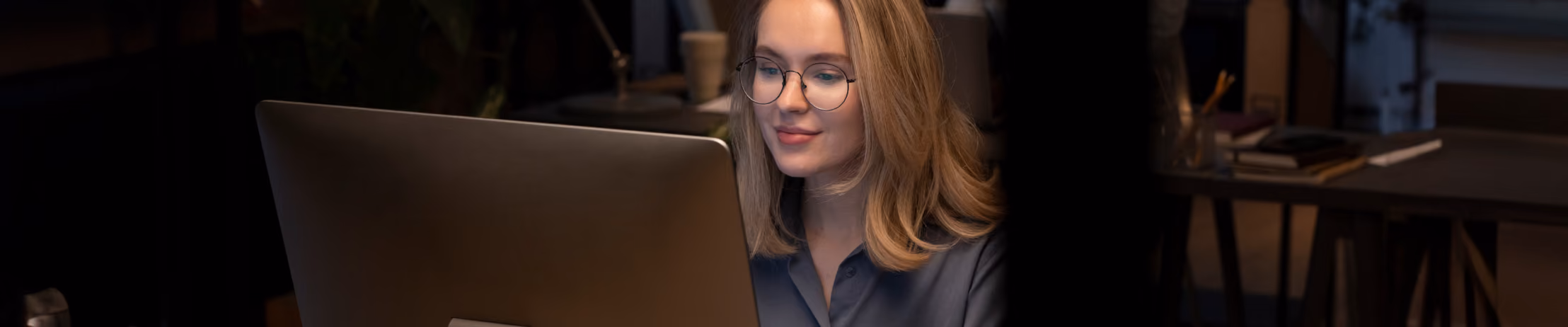 Woman researching benefits of expert chatbot development partnership on computer in a cozy office setting.