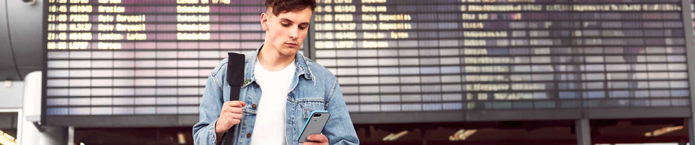 Traveler at airport checks flight on smartphone, adds baggage via app pop-up; enhancing airport efficiency and convenience.