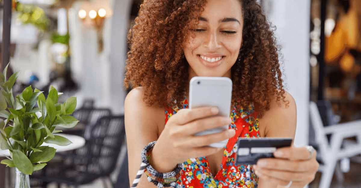 Woman using phone for online banking, holding credit card, illustrating digital transactions.