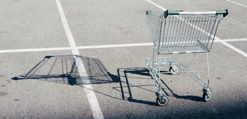 Shopping cart on empty asphalt lot, symbolizing cart abandonment in e-commerce.