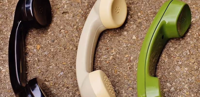 Three vintage telephone receivers on gravel surface, highlighting customer-centric communication technology.