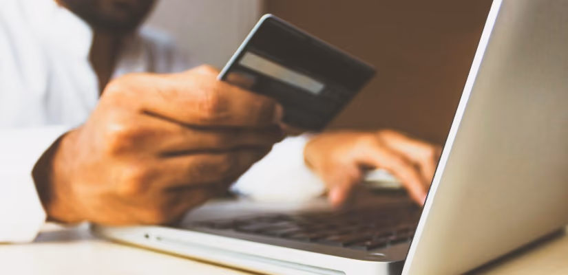 Person using credit card to shop online on laptop, ideal for e-commerce and digital payment content.