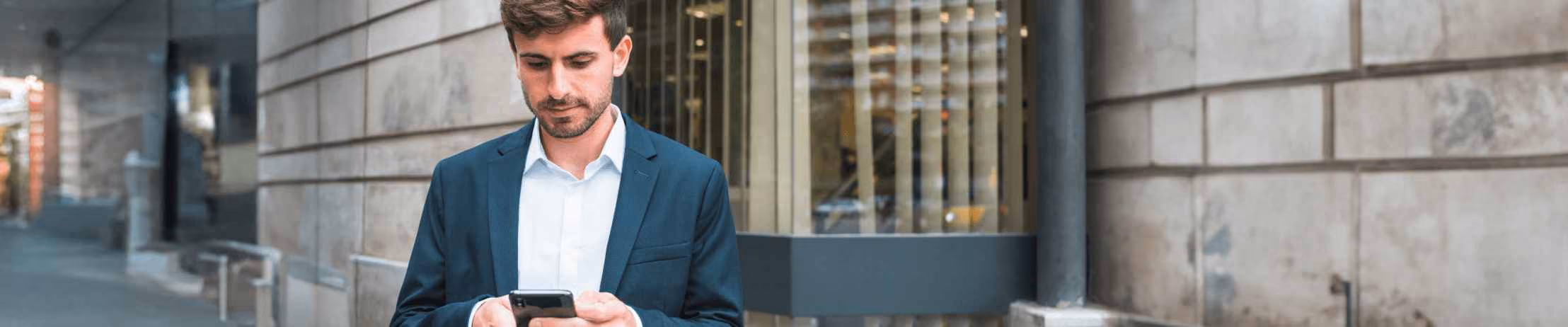 Professional businessman in blue suit using smartphone with Hub Insurance virtual assistant chat interface for vehicle claim support.