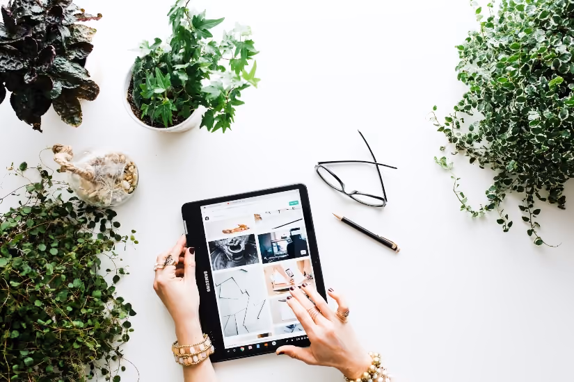 Tablet used for online shopping between green plants, ideal for omnichannel marketing content.