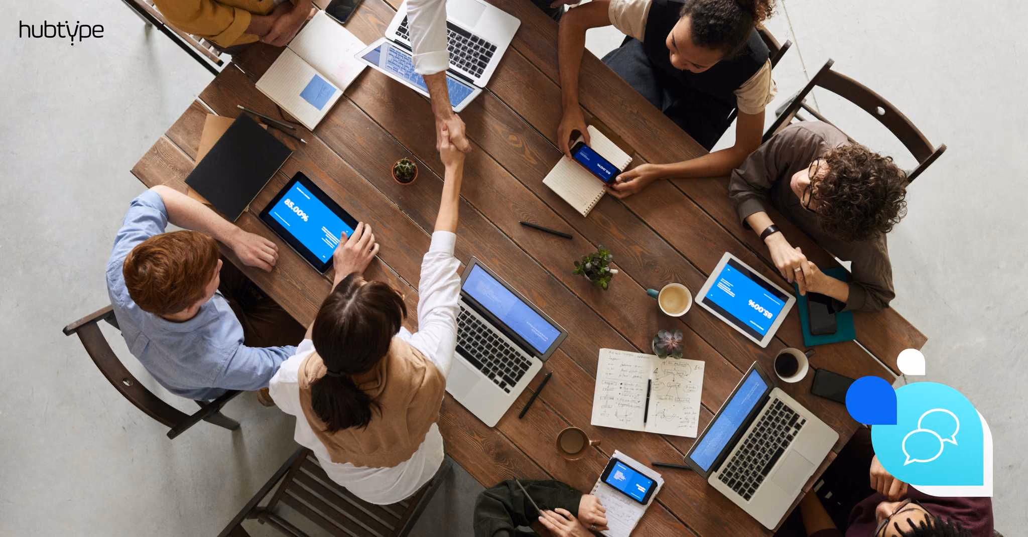 Meeting at wooden table with laptops and tablets, showcasing teamwork and collaboration for Hubtype.