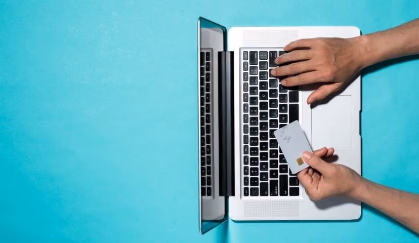 Laptop with hands holding credit card, illustrating online banking convenience.