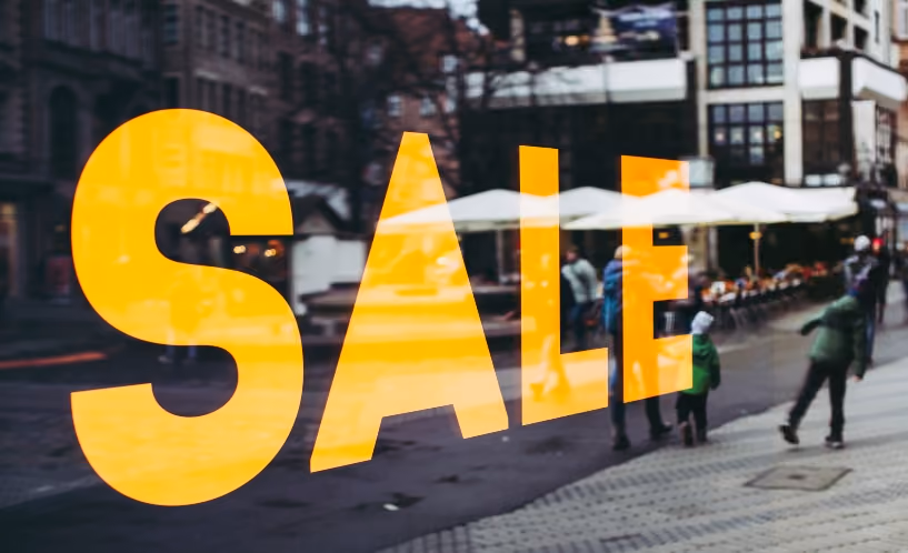 Black Friday sale sign with city street reflection in window, ideal for holiday shopping promotions.