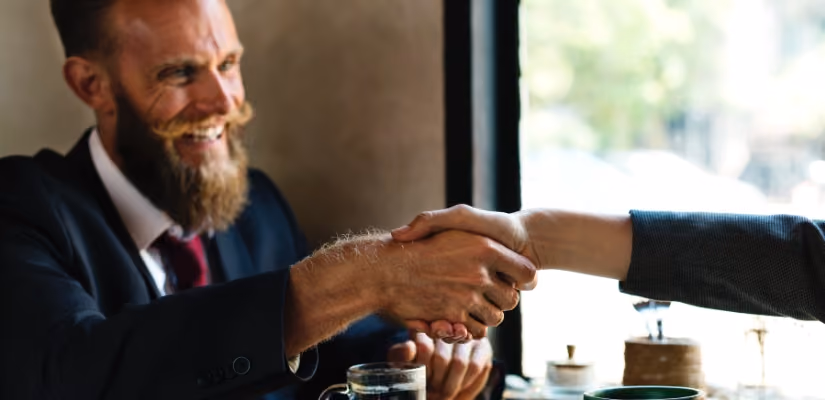 Man in suit shaking hands in a business meeting, symbolizing professional agreement.