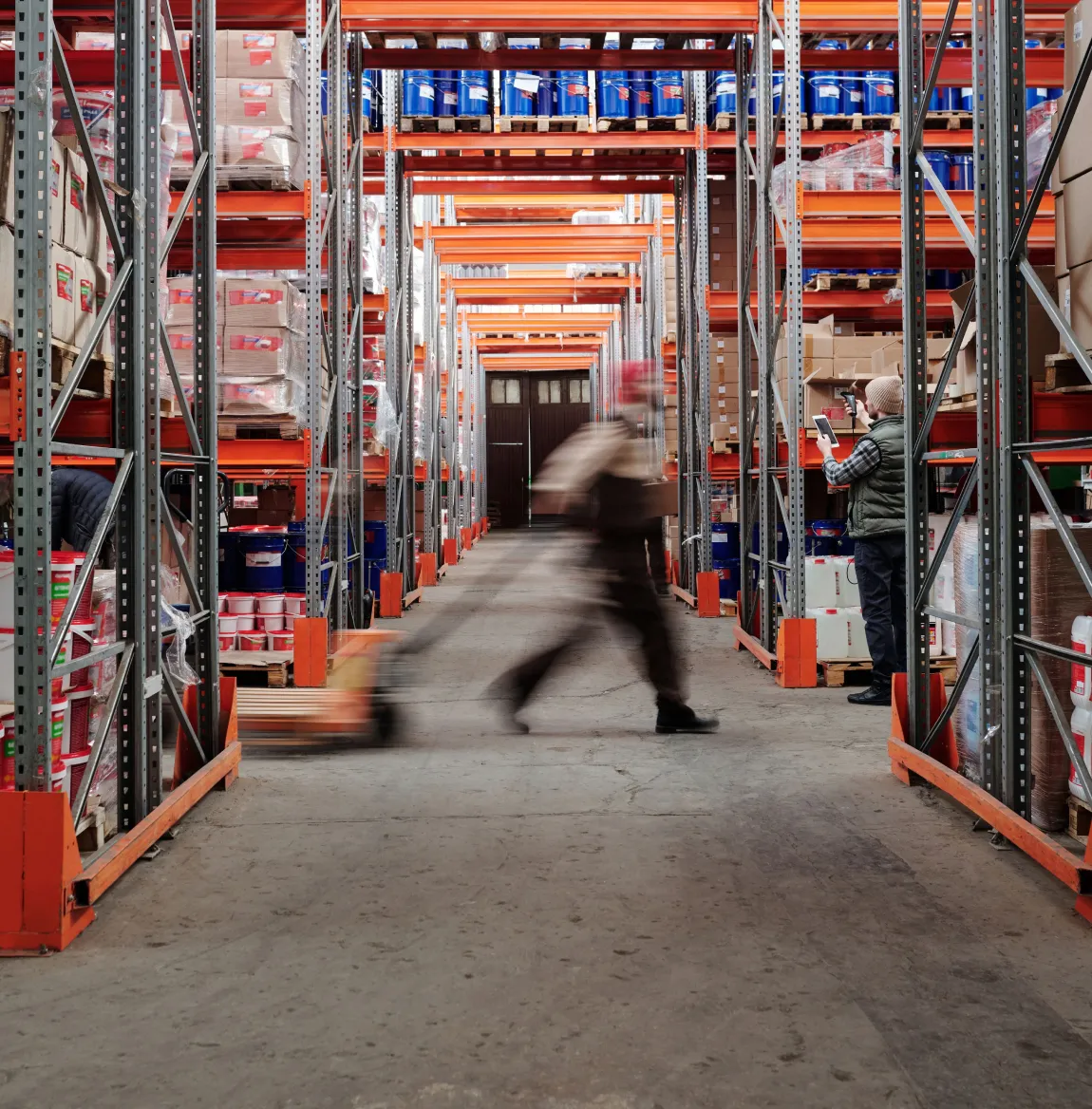 Worker moving a pallet down a warehouse aisle