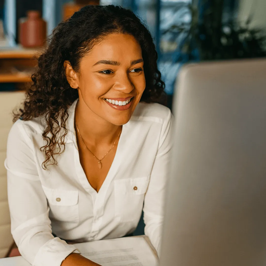 Smiling woman in a white shirt works on a computer.