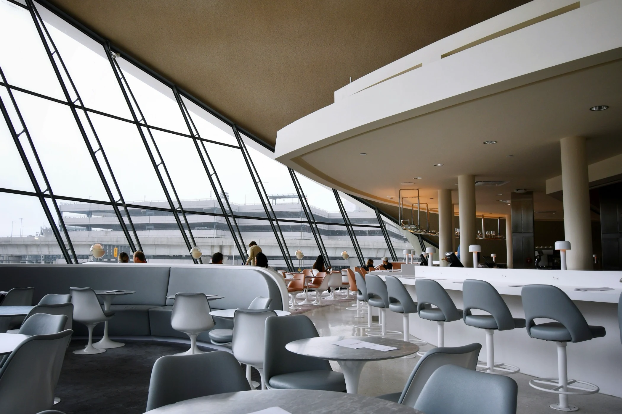 people sitting on white chairs inside building. The restaurant in the TWA hotel.