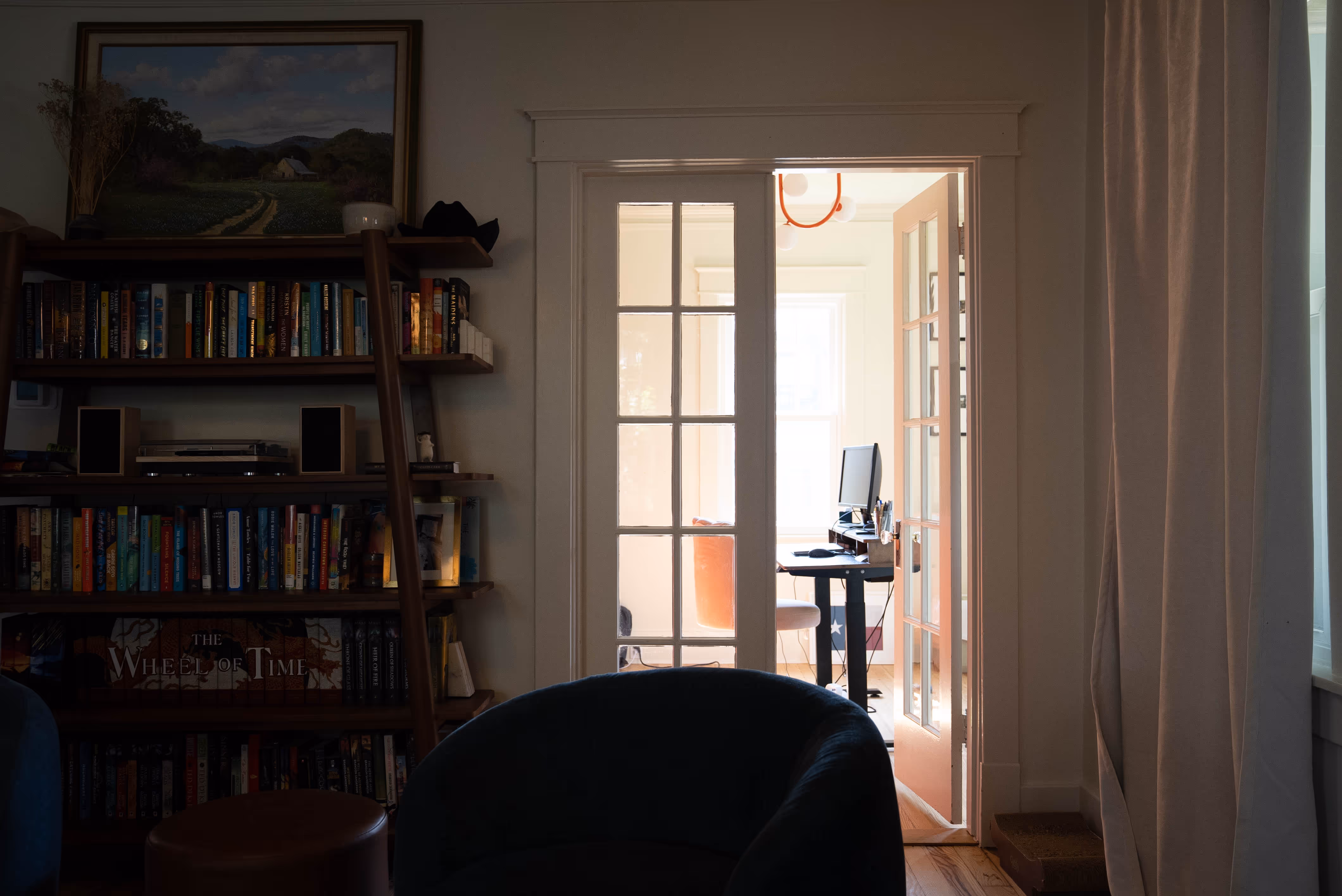 Living room with door open to a bright office space.