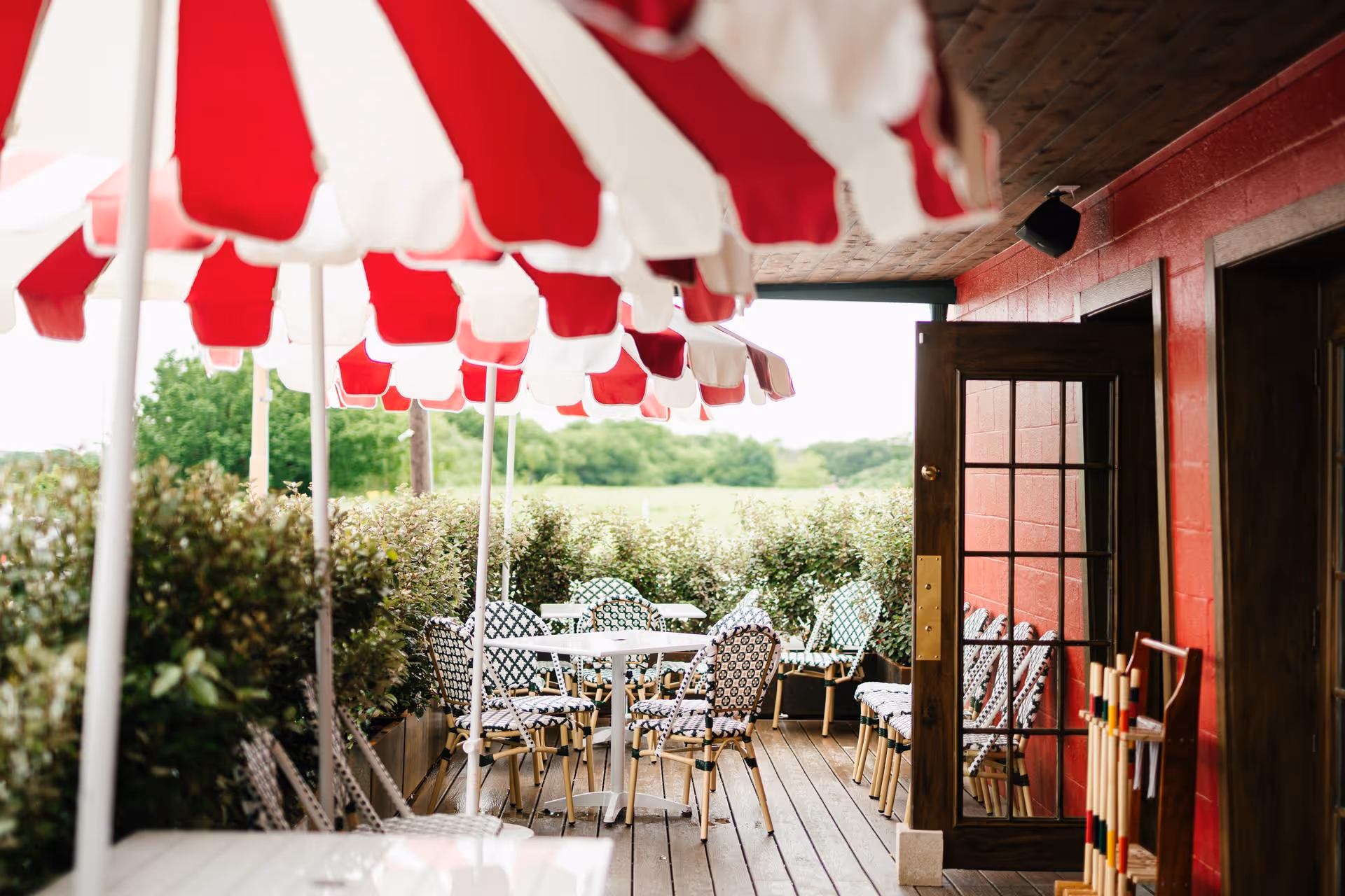 Stewart's outdoor patio with red and white striped umbrellas, bistro chairs, and croquet mallets overlooking the lawn