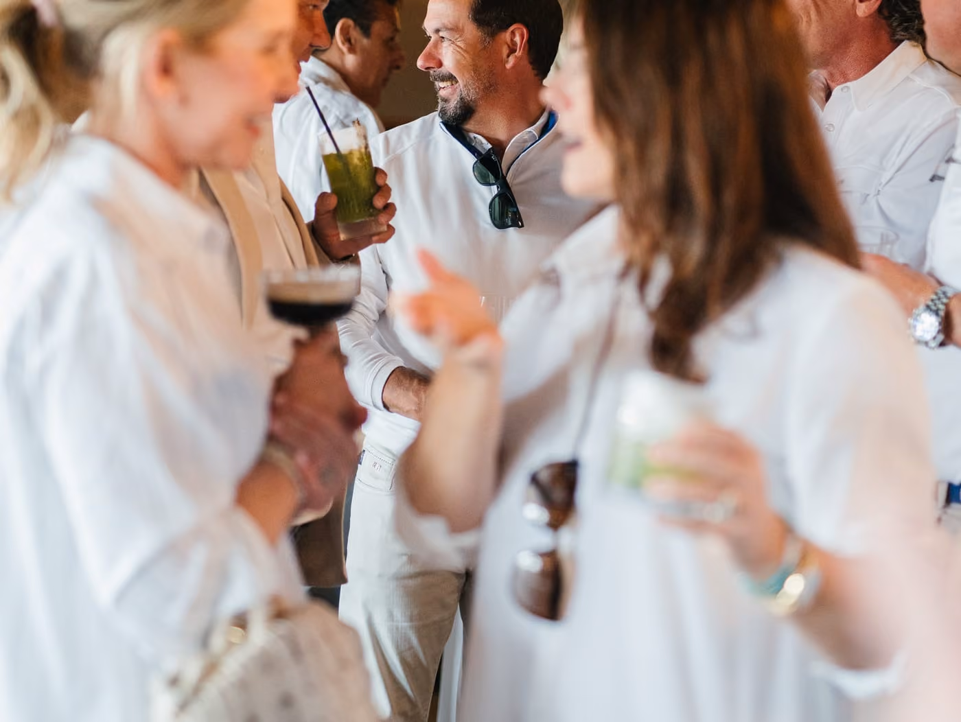 Guests in white mingling with cocktails in Stewart's warmly lit private dining room