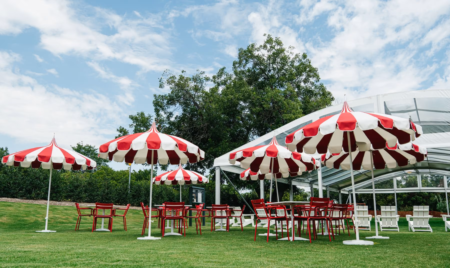 Red and white striped umbrellas and lawn seating on Stewart's open croquet lawn