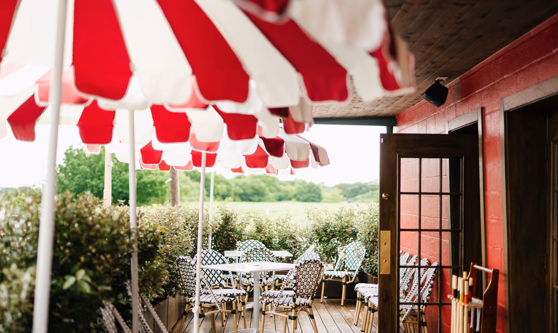 Striped umbrella shading bistro tables on Stewart's red-walled patio
