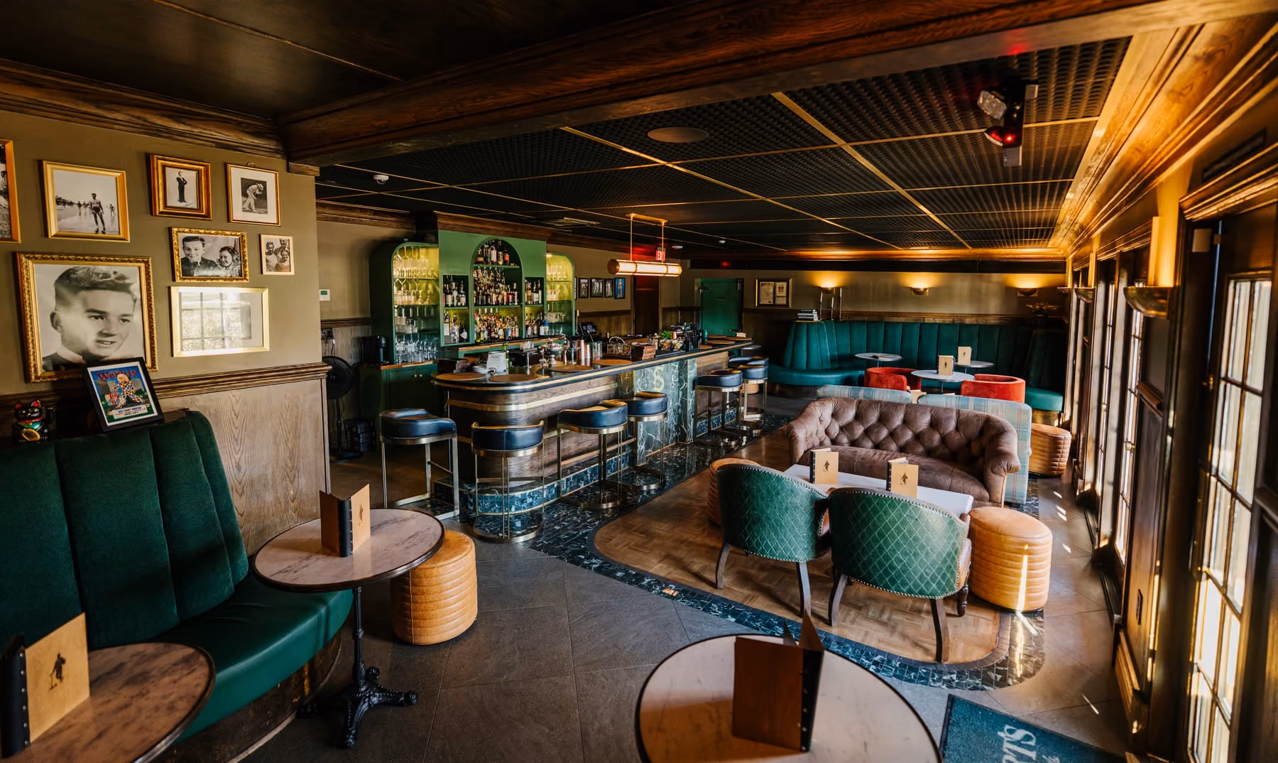 Green velvet banquettes and gallery walls in Stewart's indoor lounge