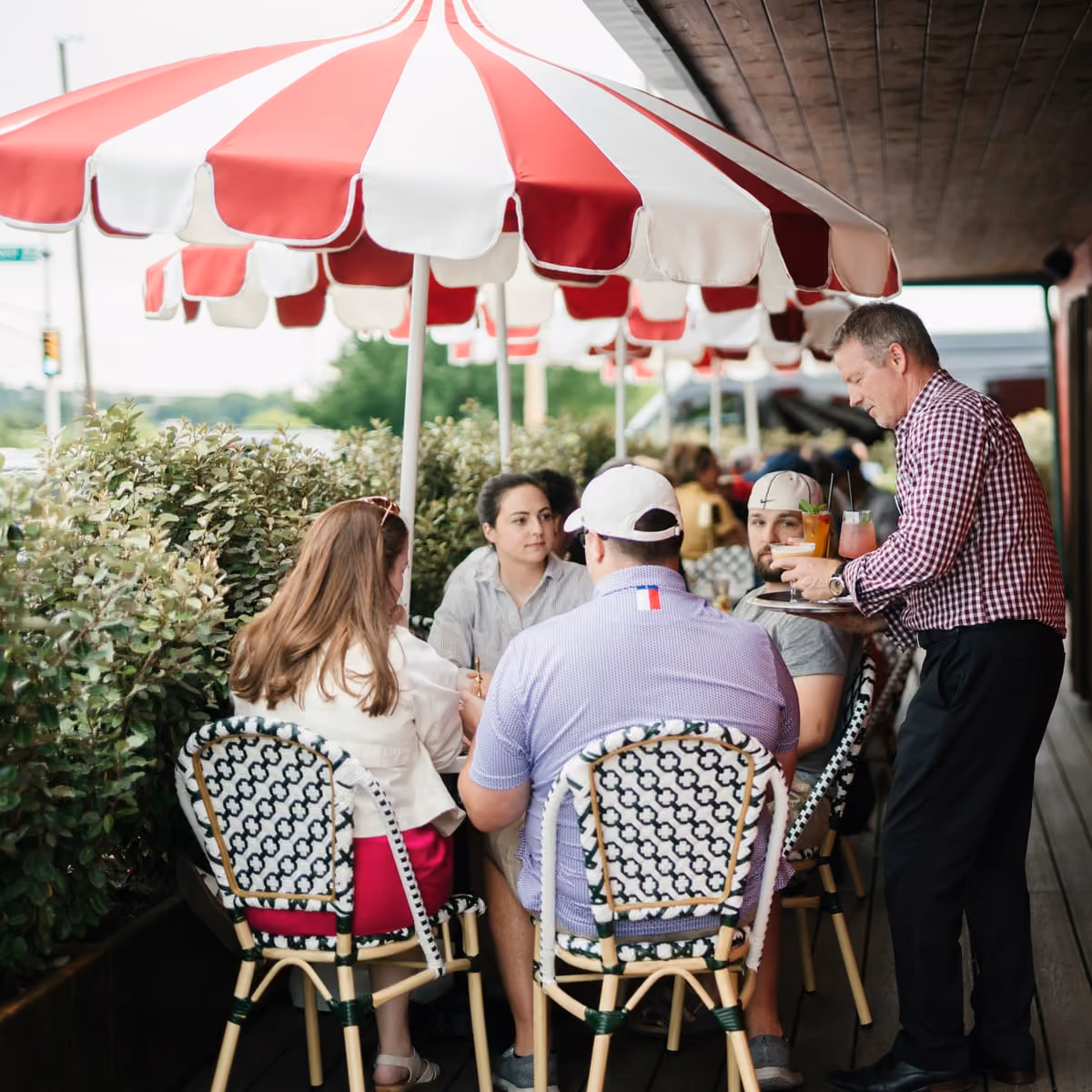 Guests gathered under red and white striped umbrellas on the patio