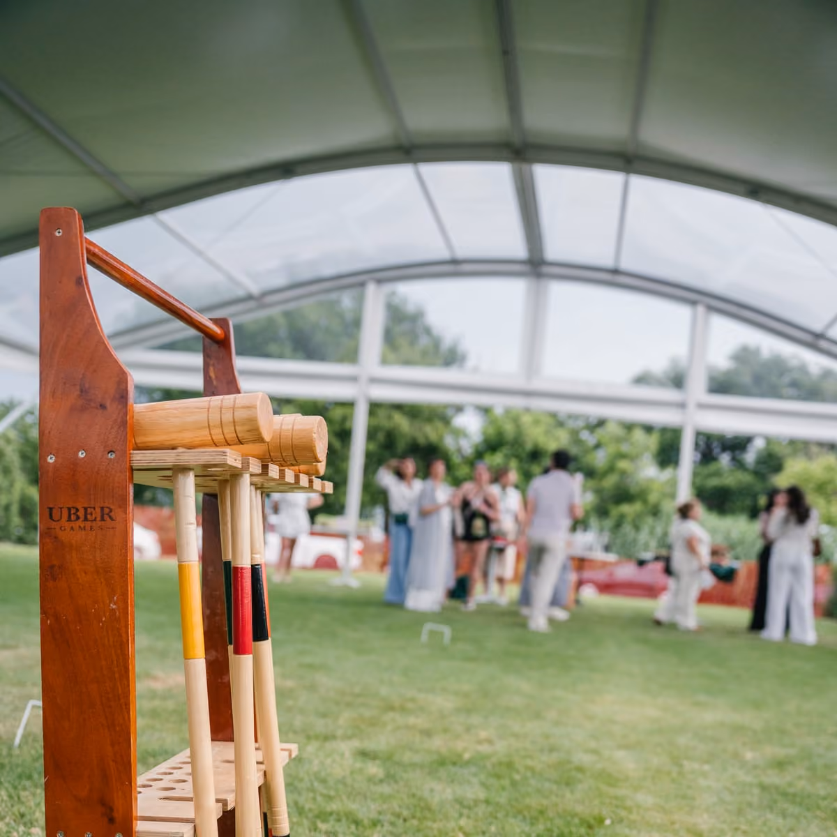 Wooden croquet mallet caddy on the lawn with guests playing behind