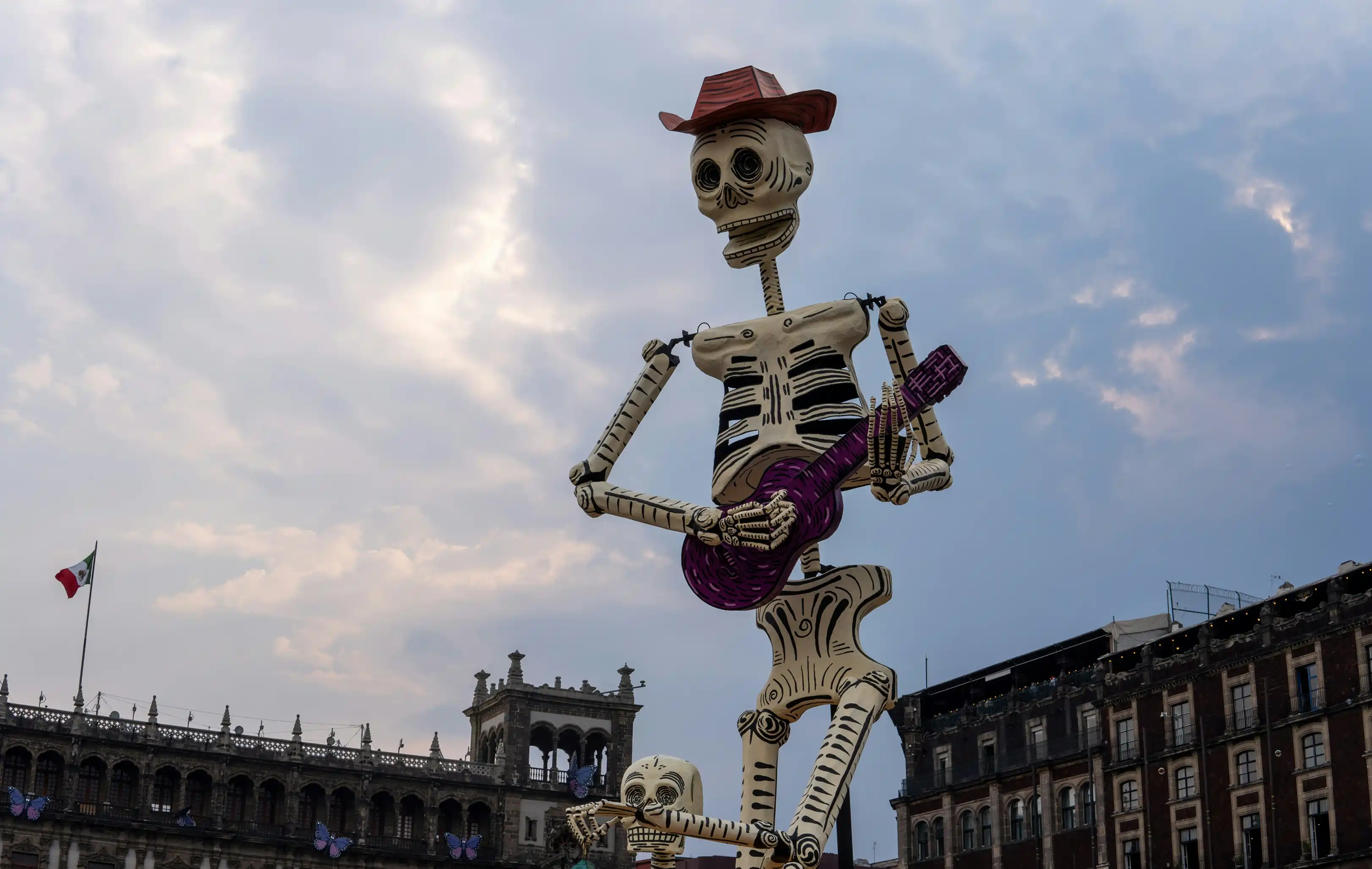 Esqueleto gigante con sombrero tocando guitarra en plaza, decoración de Día de Muertos