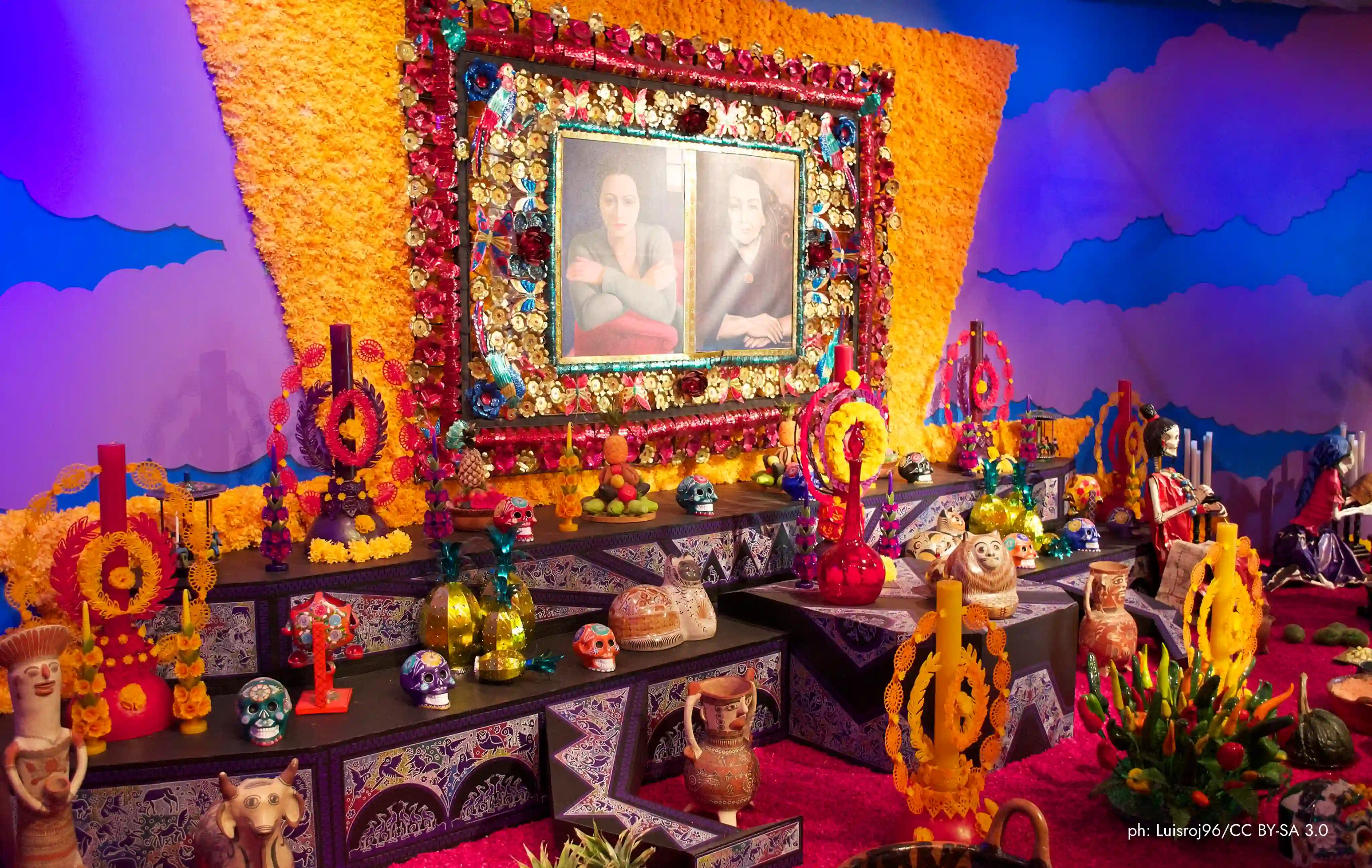 Colorida ofrenda de Día de Muertos con flores, velas y fotos