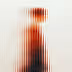 Abstract vertical blur pattern with warm orange, black, and beige tones.