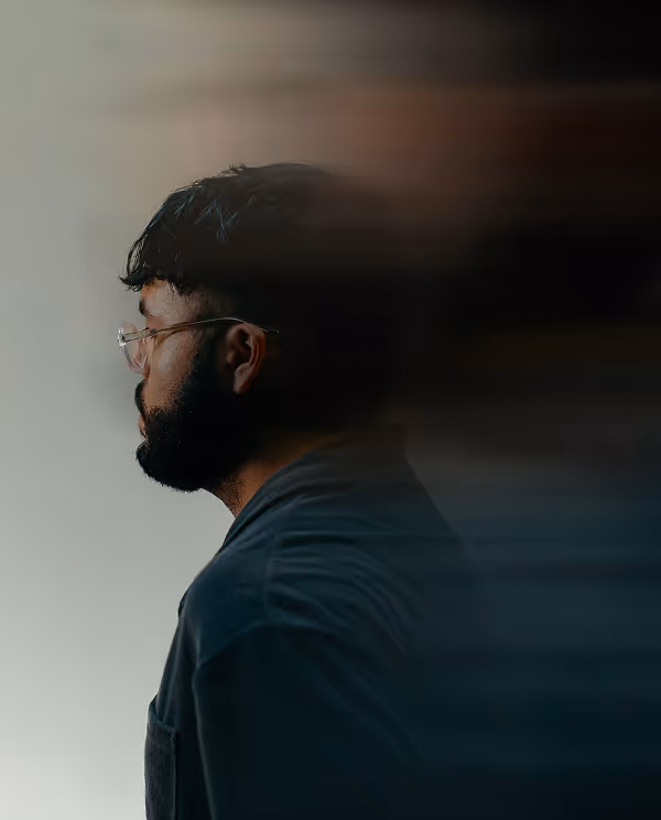 Profile of a bearded man with glasses facing left, with motion blur extending from the back of his head.