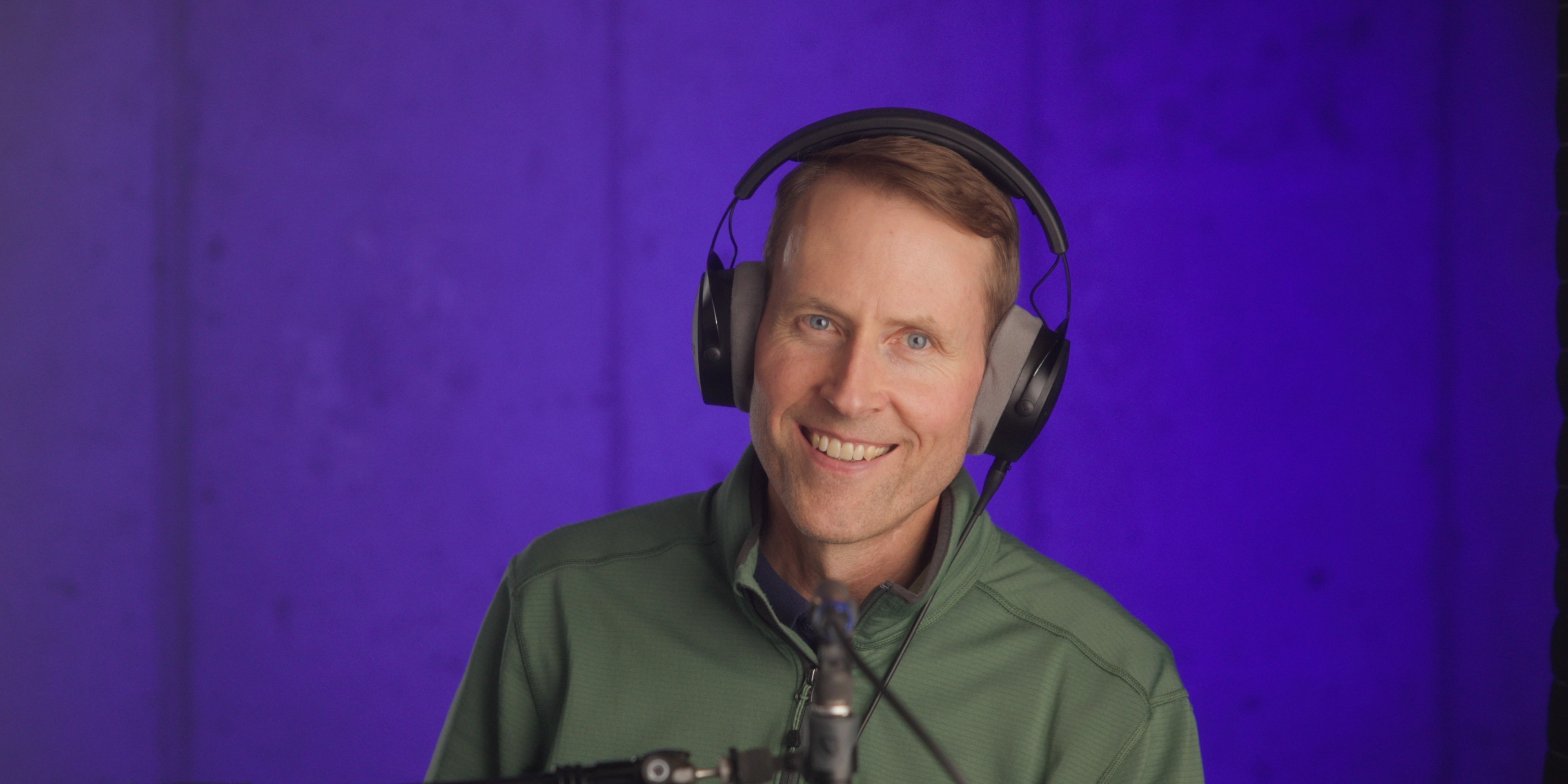 Photo of Curtis Judd wearing headphones and sitting in front of a microphone.