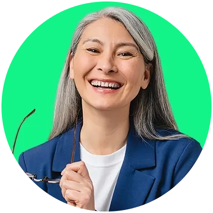 Portrait of a smiling woman with long grey hair, wearing a blue blazer over a white shirt, holding a pair of glasses.