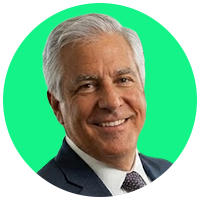 Portrait of a smiling older man with short, white hair, wearing a suit.