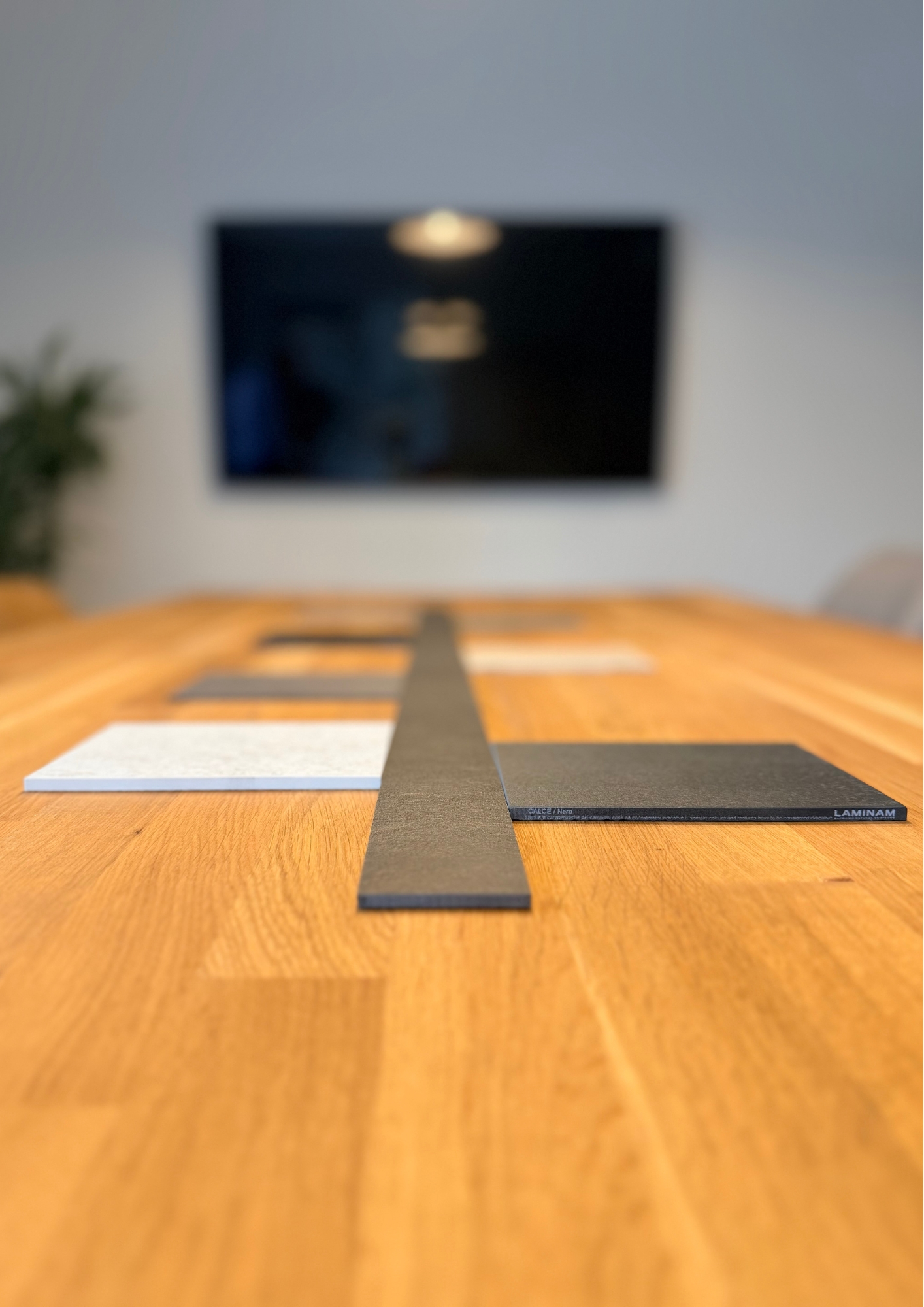 Wood flooring samples displayed on table with TV mounted on wall behind