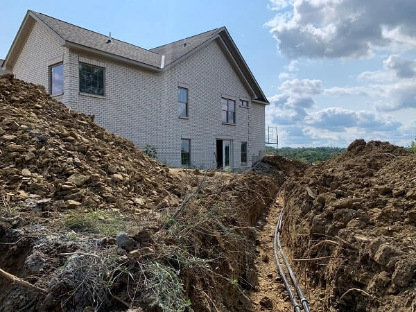Geothermal heating and cooling system being buried by a residential home